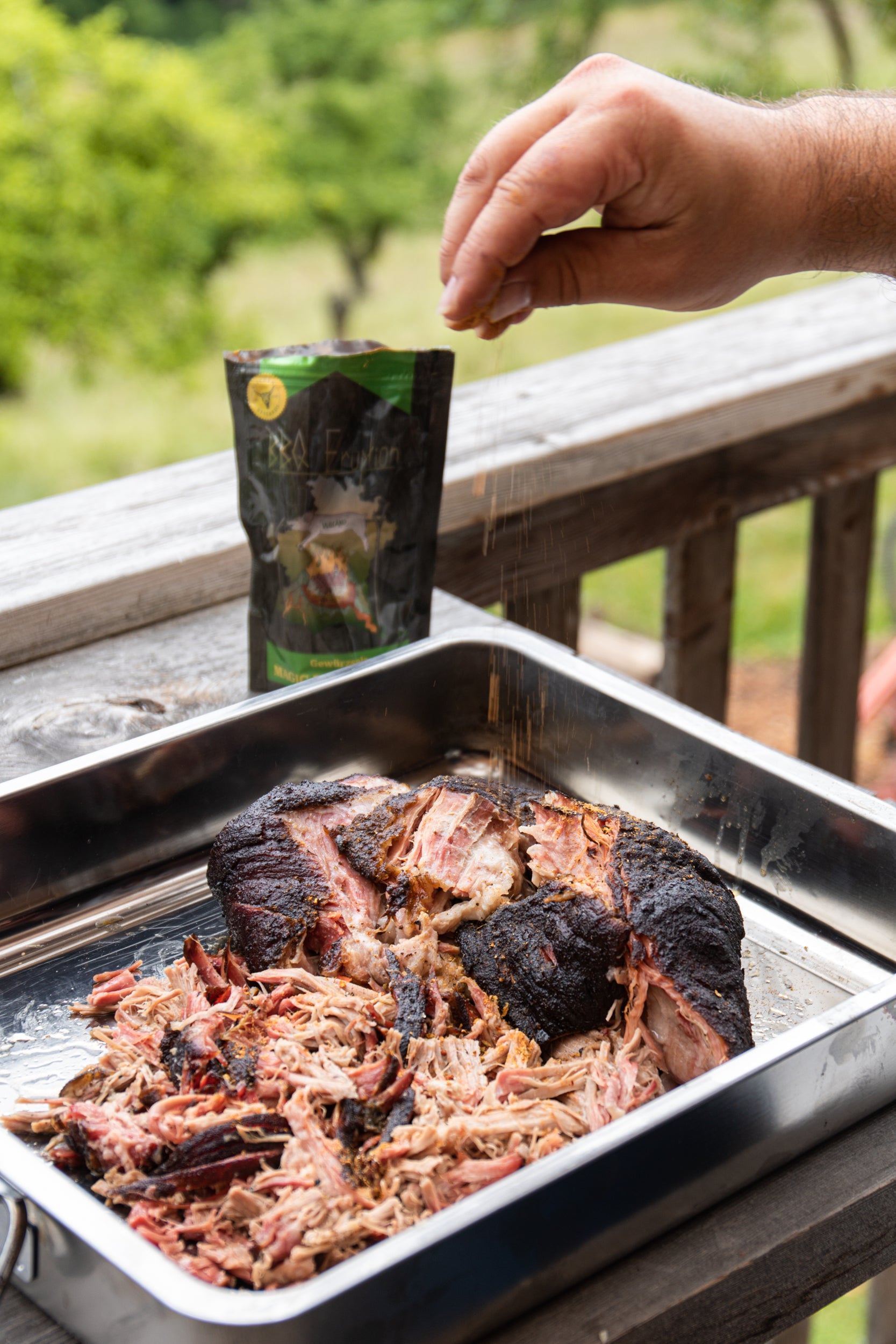 BBQ Eruption Magic Dust Gewürz von Kitchen Bastards bei der Anwendung auf Fleisch am Grill für würzige und scharfe BBQ-Gerichte
